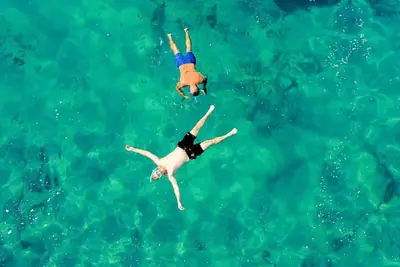 Aerial view of two guests snorkelling in turquoise water during a boat trip in Tenerife