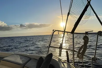 Goldener Sonnenuntergang vom Deck einer Segelyacht, vorne Segel und Takelage