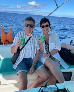Lächelndes Paar mit kalten Getränken an Deck einer Segelyacht auf Teneriffa