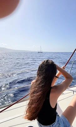 Guest with long hair looking out to sea from the side of the yacht