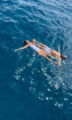 Two guests floating on their backs in deep blue water at the swim stop