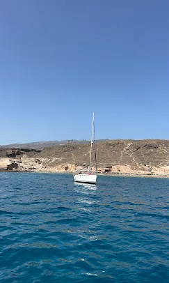 Voilier au mouillage dans une baie calme sous des collines arides, sud de Tenerife